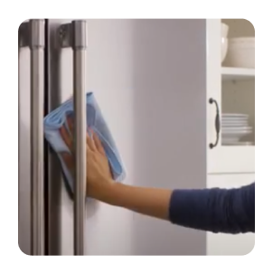 Hand wiping a stainless steel refrigerator with a dry cloth