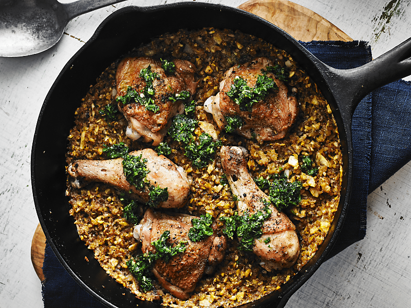 Cast iron skillet filled with baked chicken and rice medley
