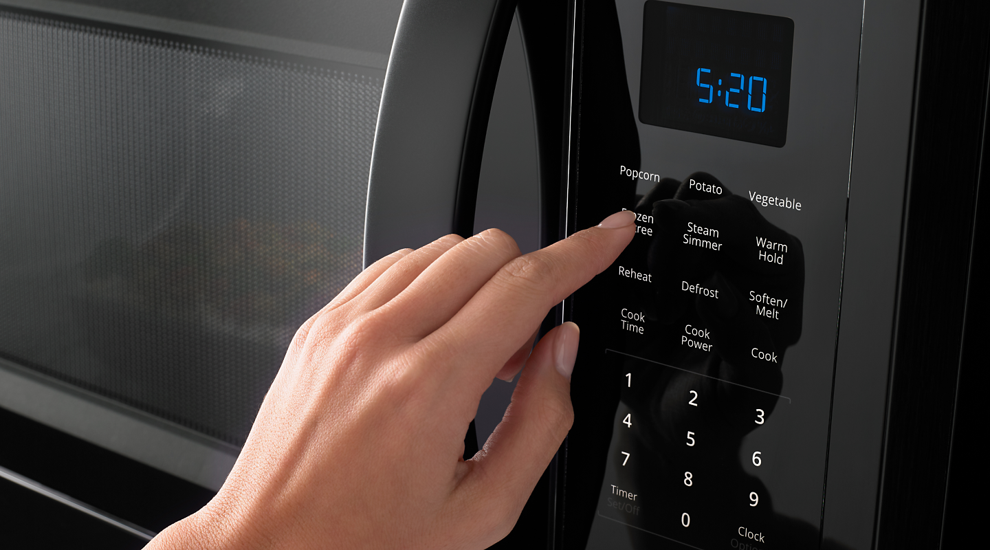 Person pressing button on microwave