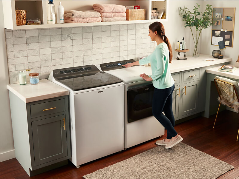 A woman making a cycle selection on a Whirlpool® dryer