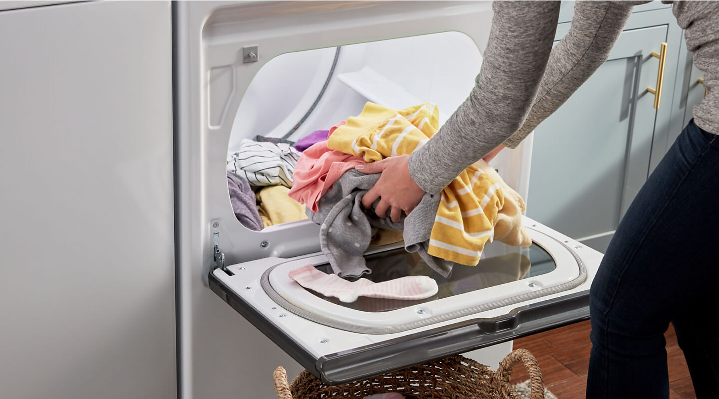A person unloading laundry from a dryer