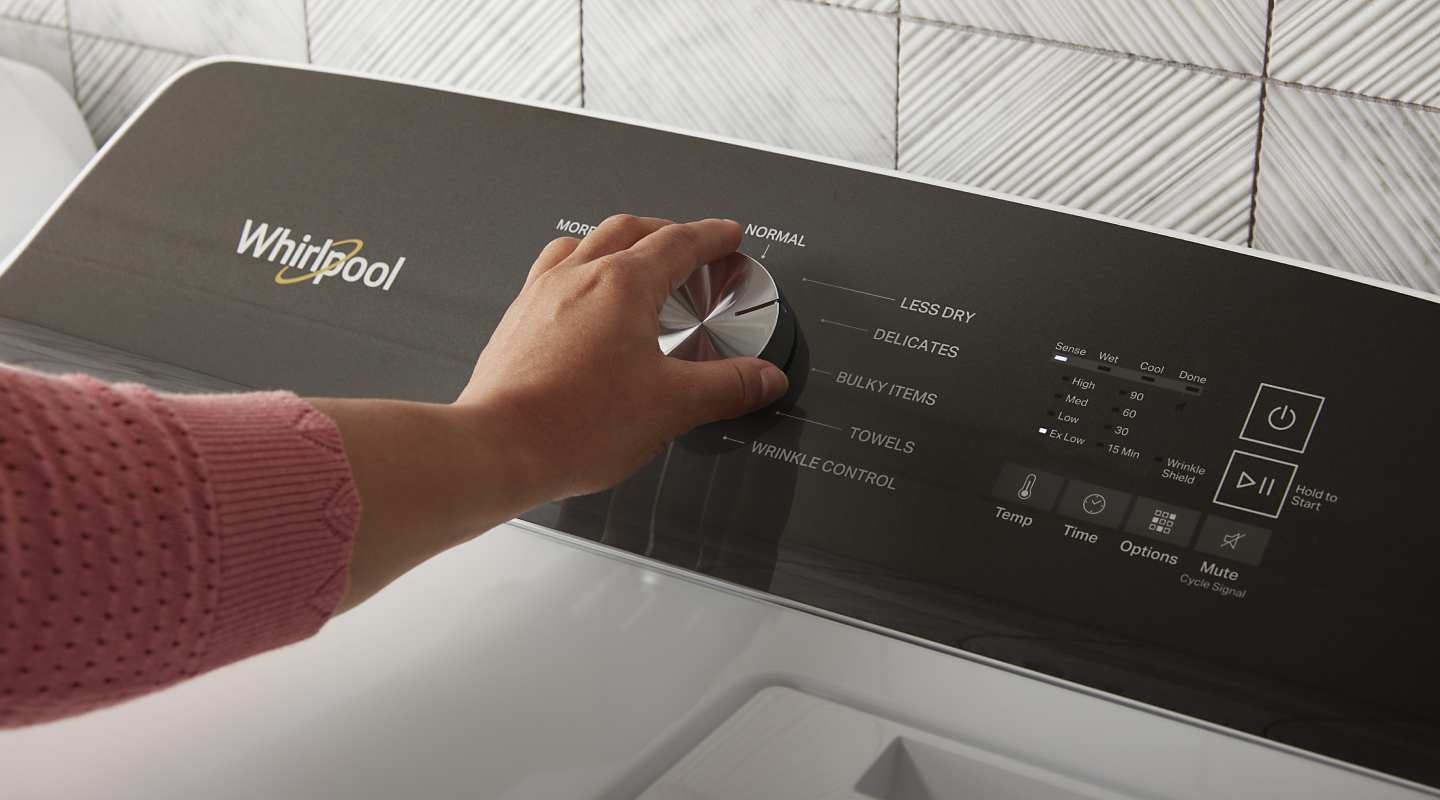 Hand selecting a cycle setting on a Whirlpool® dryer