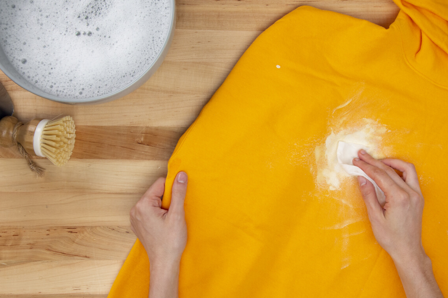 用纸巾在黄色运动衫上用手吸干白色油漆