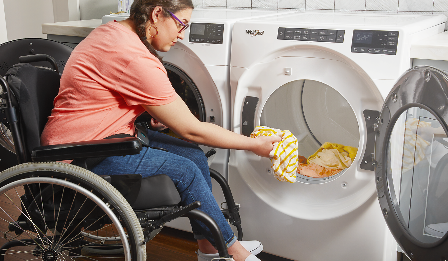 A person putting clothes into a Whirlpool® dryer