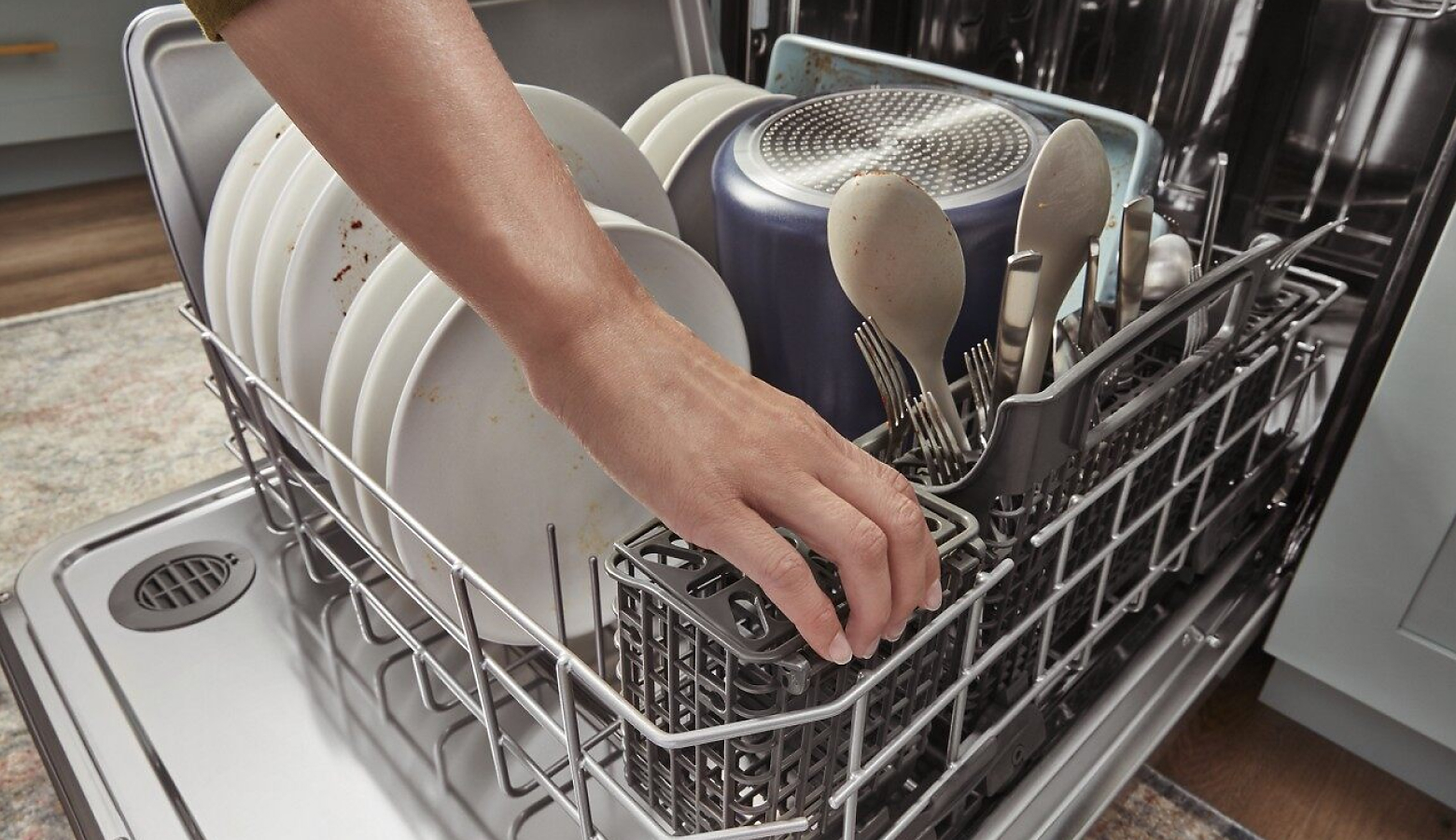 Hand reaching into a loaded dishwasher