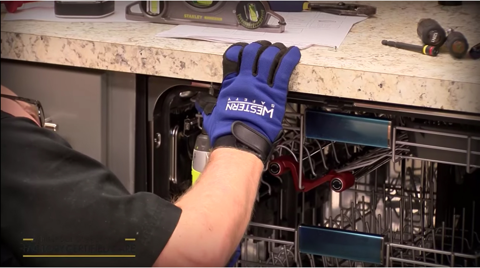 Hand touching countertop above an open dishwasher