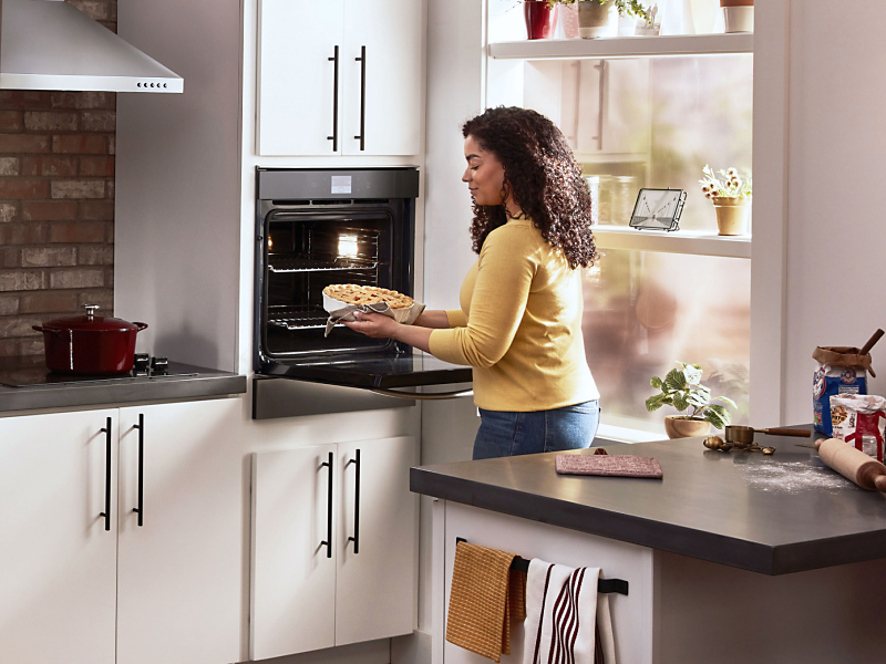 Woman using a Whirlpool®  single wall oven in a modern kitchen