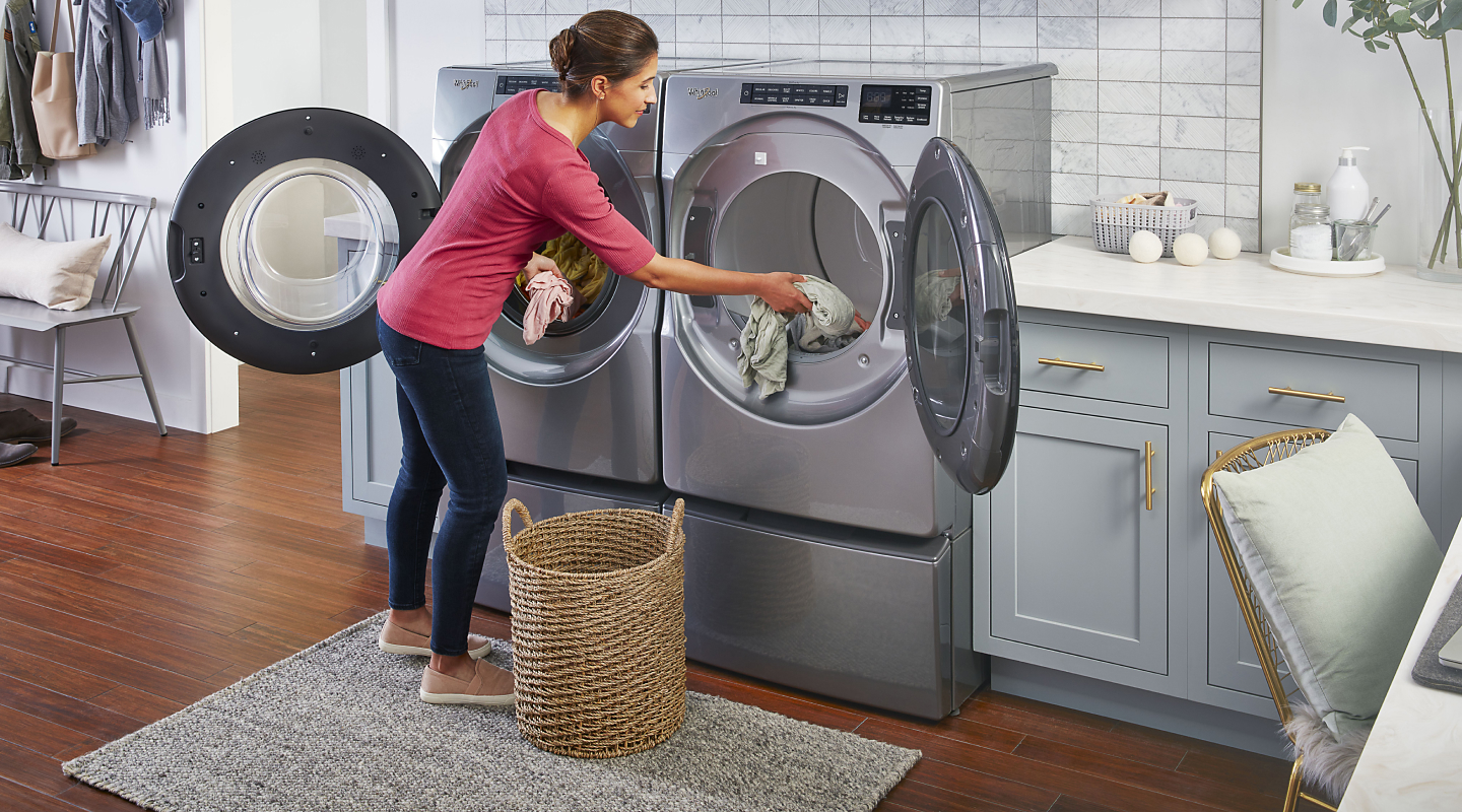Person moving clothes from washer to dryer