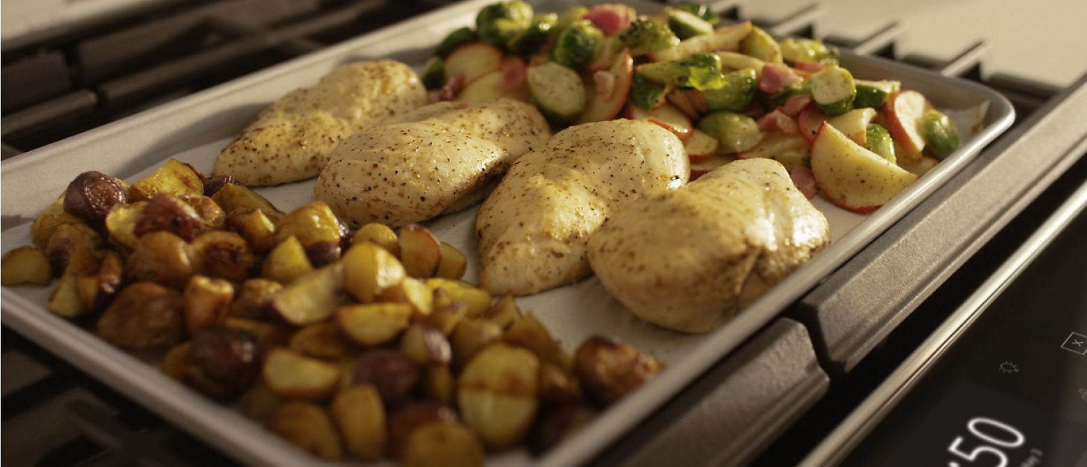 Close up of a sheet pan with chicken breasts and vegetables 
