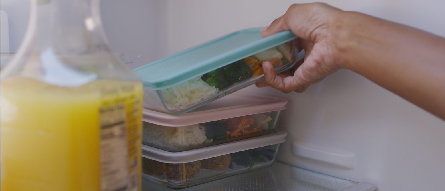 Hand storing meal prep container into fridge