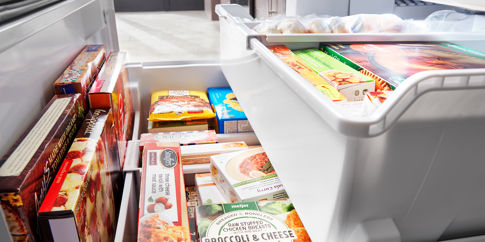 Bottom freezer drawer opened showing organized freezer bins