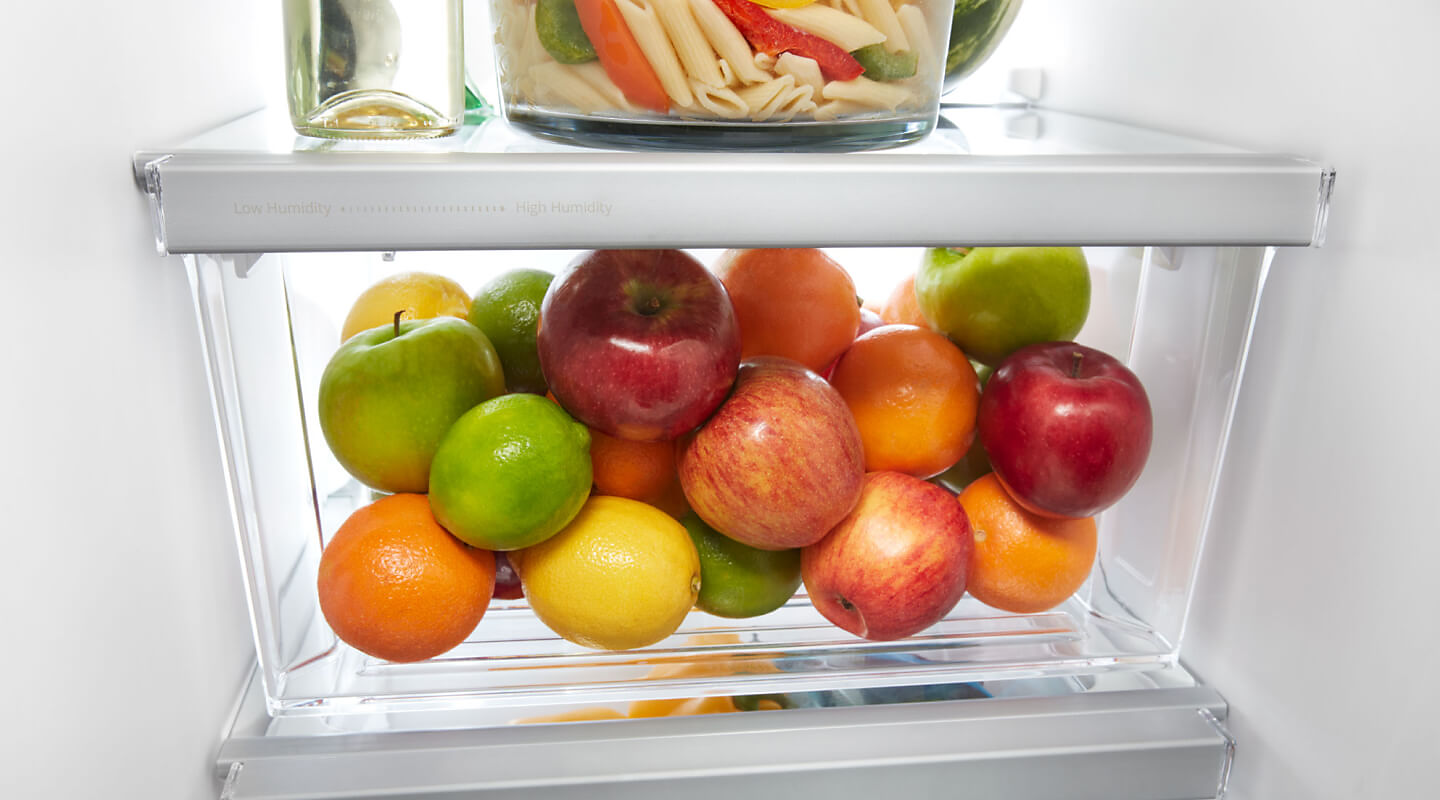 A closeup of a Whirlpool® side-by-side refrigerator crisper drawer with fruit 