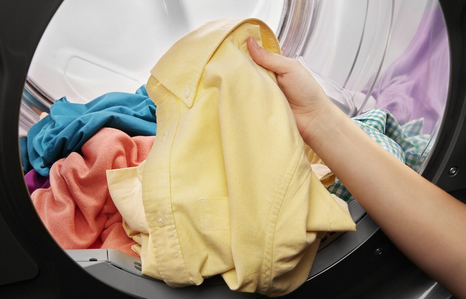 Hand pulling yellow shirt out of a dryer