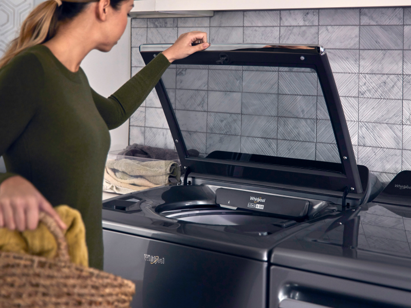A woman opening a top load washer