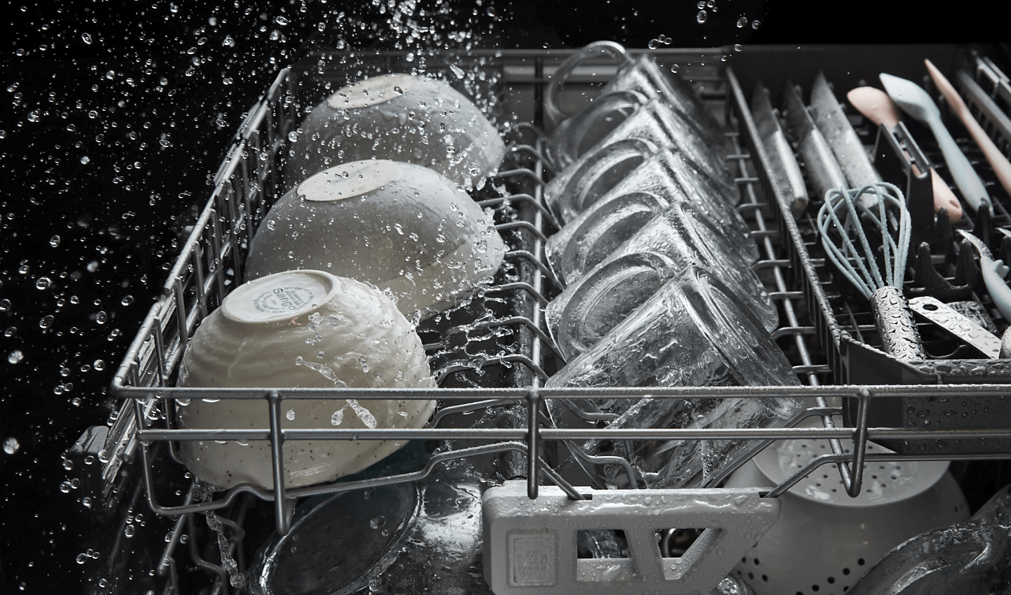 A dishwasher rack filled with dishes being cleaned