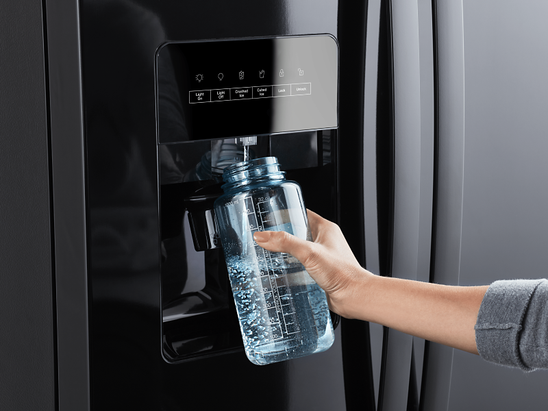 Person filling a reusable water bottle from a refrigerator water dispenser