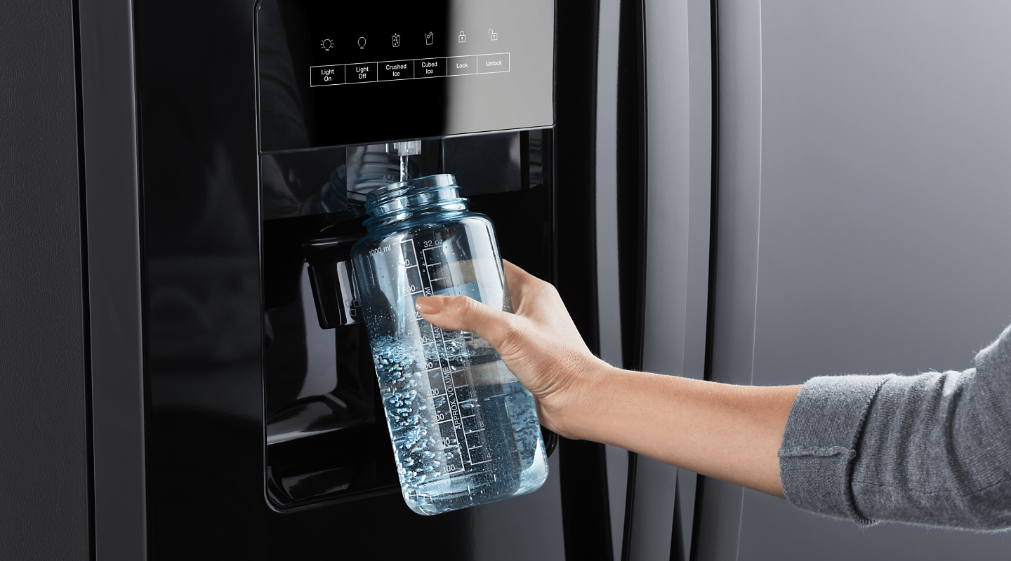 Person filling a reusable water bottle from a refrigerator water dispenser