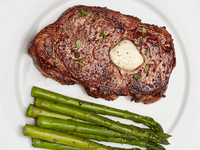 A seared steak with butter and roasted asparagus 