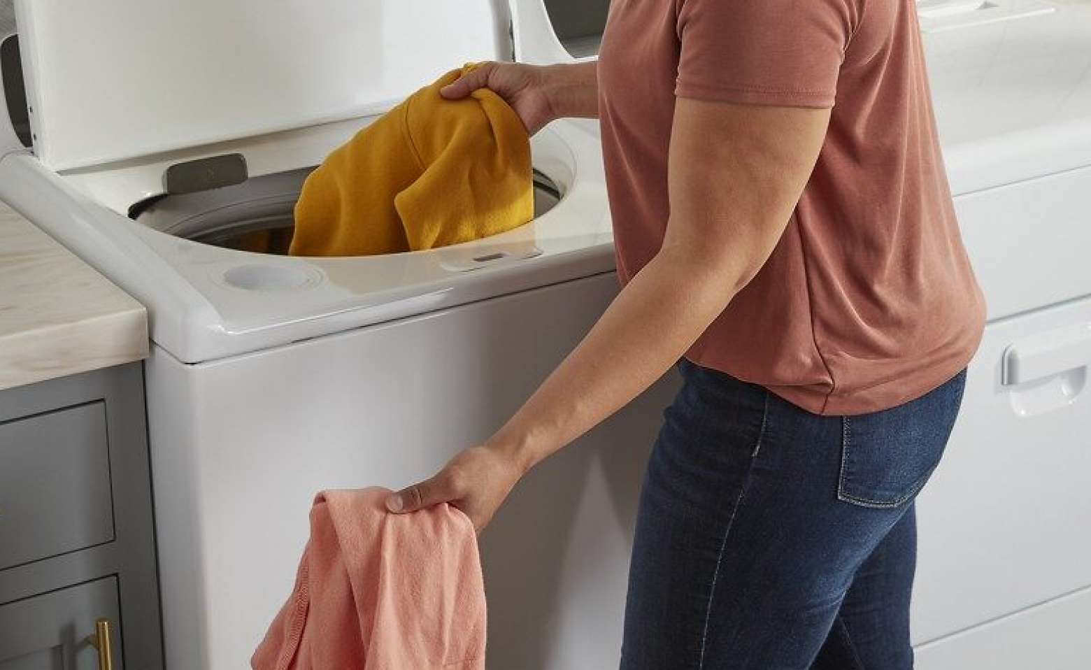 Person loading a washing machine with laundry