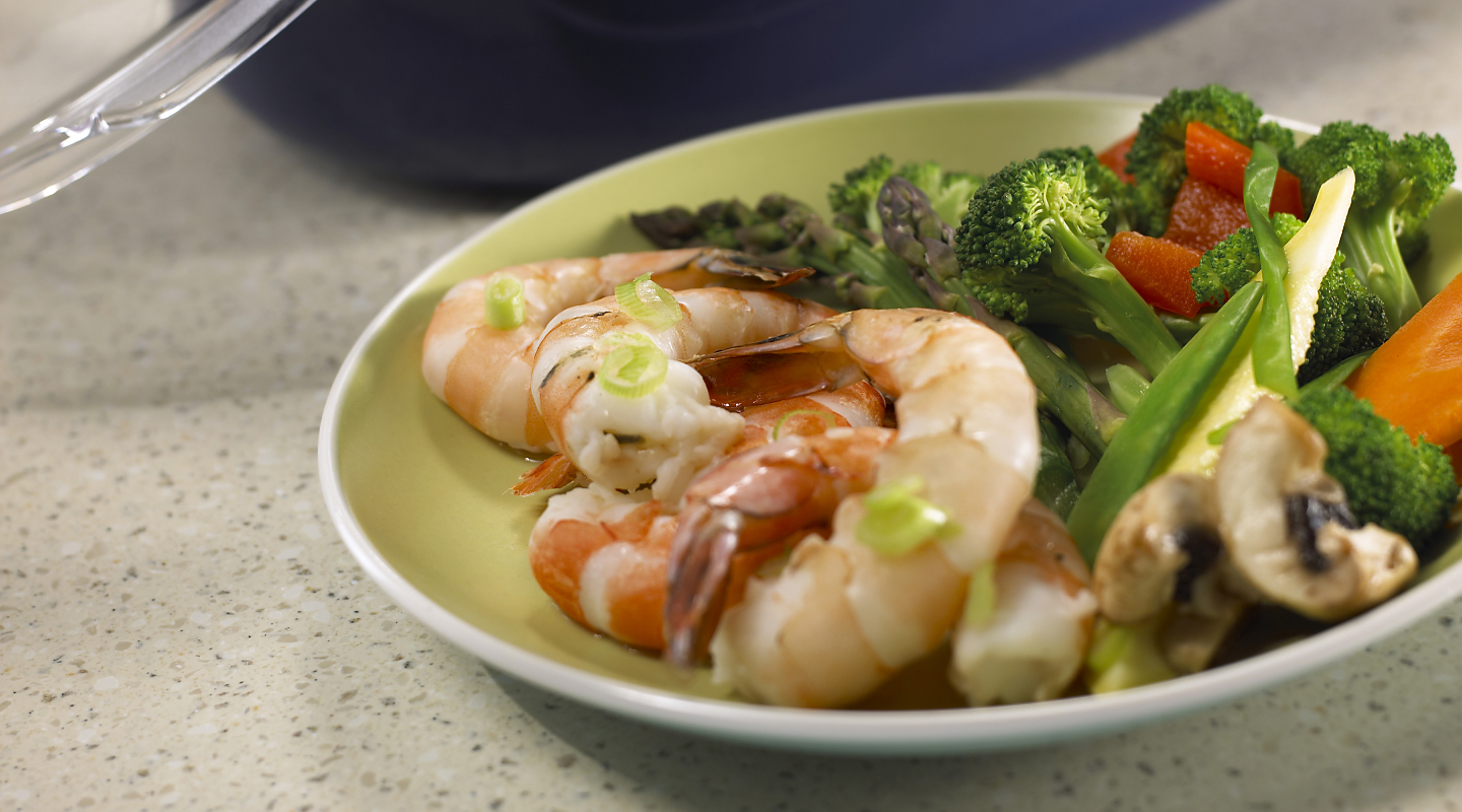 Steamed vegetables on a plate with grilled shrimp