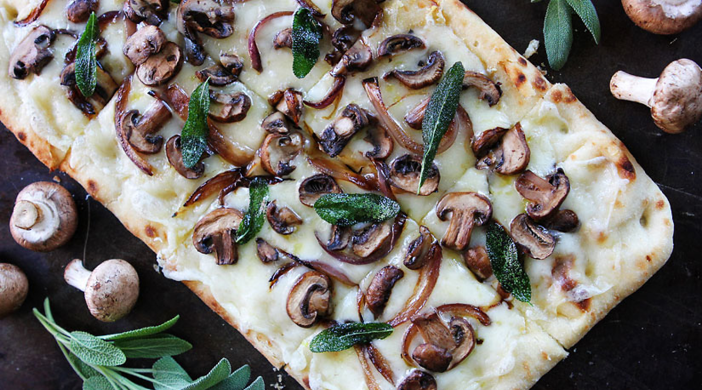 披萨饼上面有奶酪、蘑菇和香草