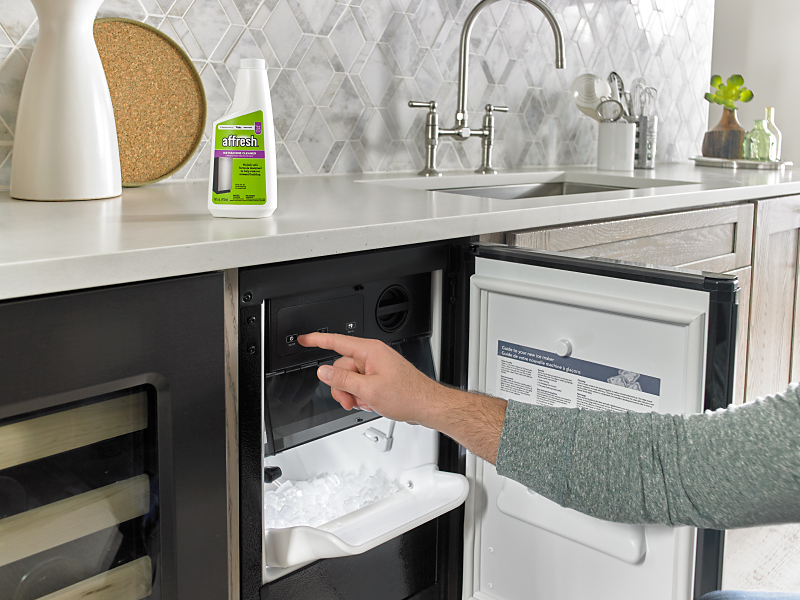 Person opening a built-in icemaker next to affresh® cleaner