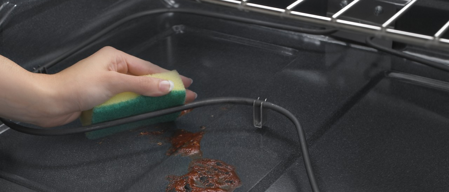 Hand cleaning oven floor with a sponge