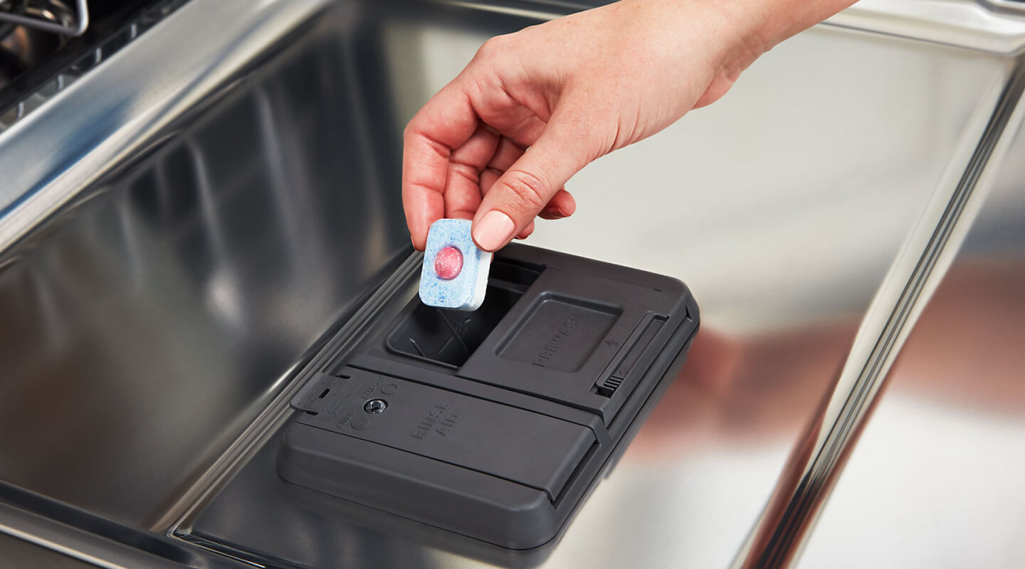 Person placing dishwasher pod into detergent dispenser