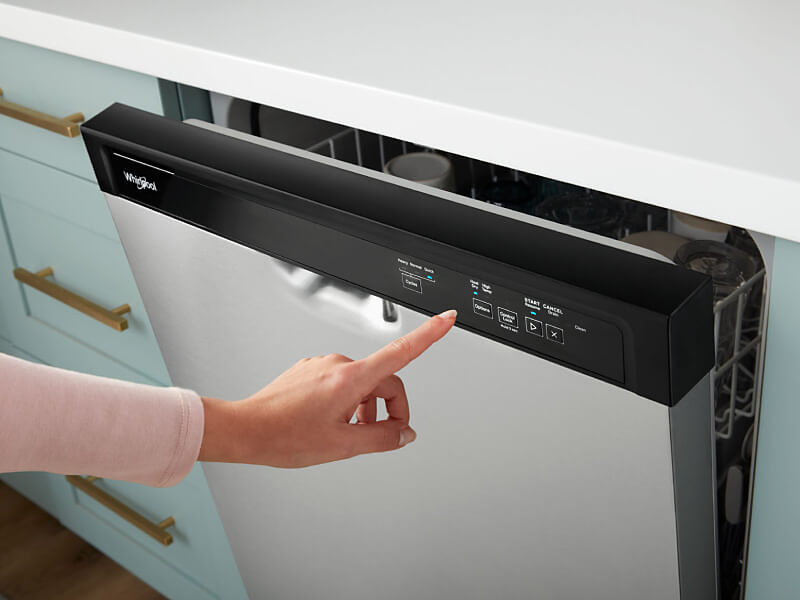 Person selecting settings on front control panel of a Whirlpool brand dishwasher