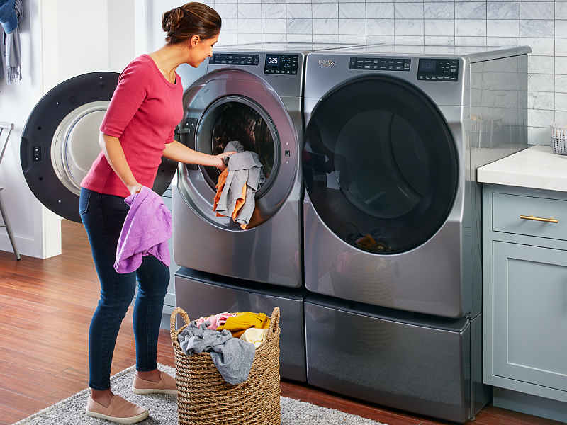 Woman loading laundry into a slate gray Whirlpool® washing machine
