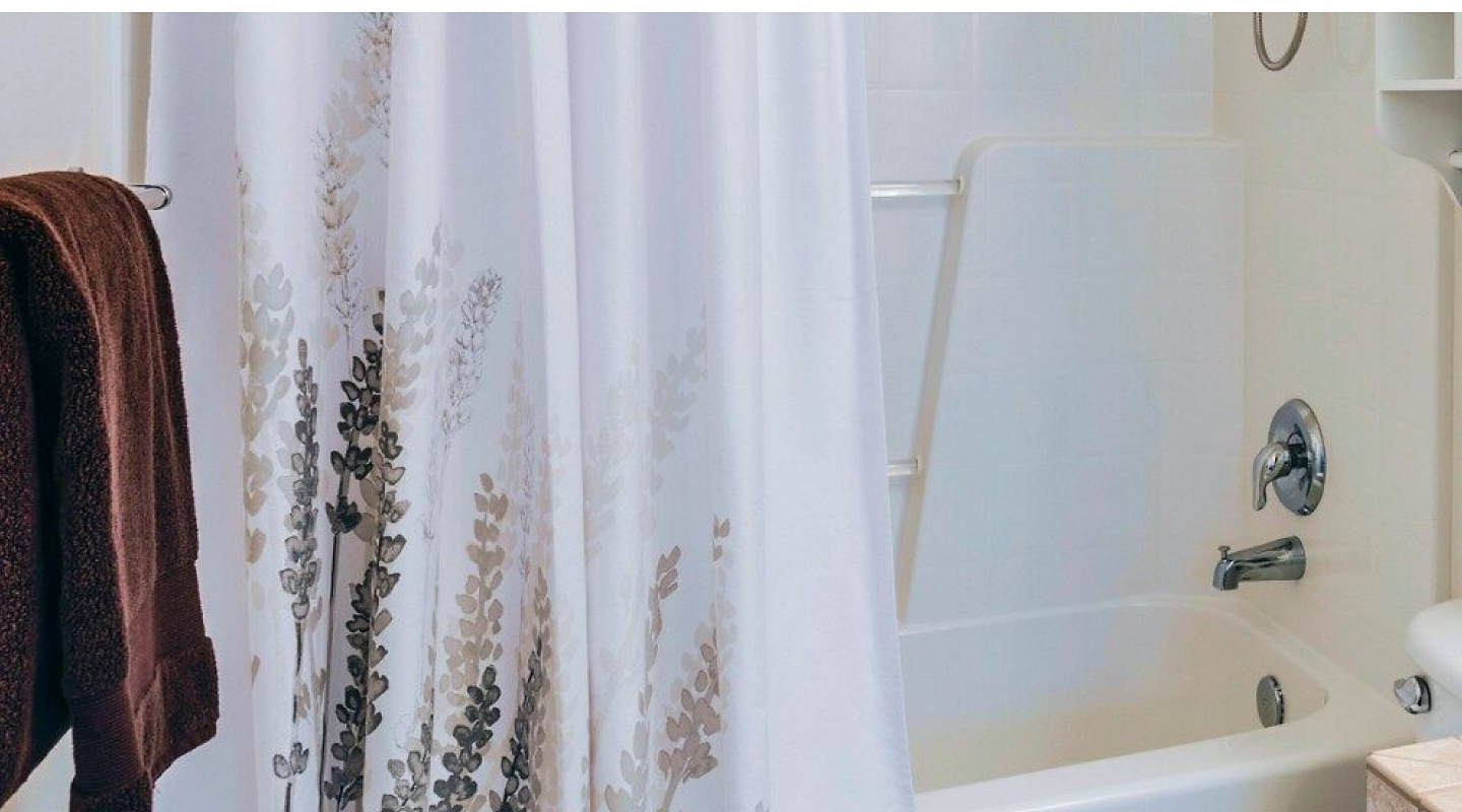 A hanging shower curtain with a design at the bottom. 