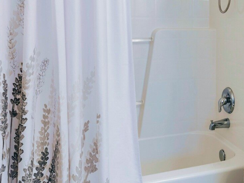 A hanging shower curtain with a design at the bottom. A hanging shower curtain with a design at the bottom.