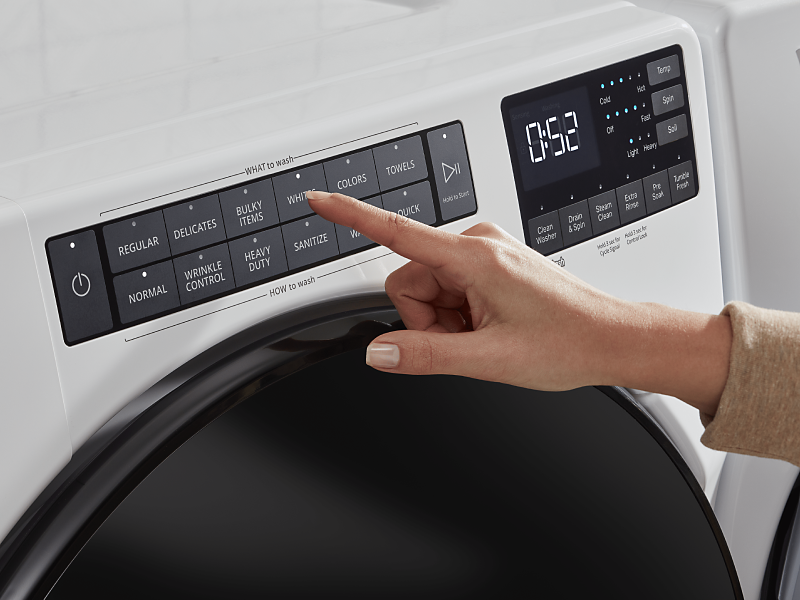 Woman selecting a wash cycle on a white front-loading washer