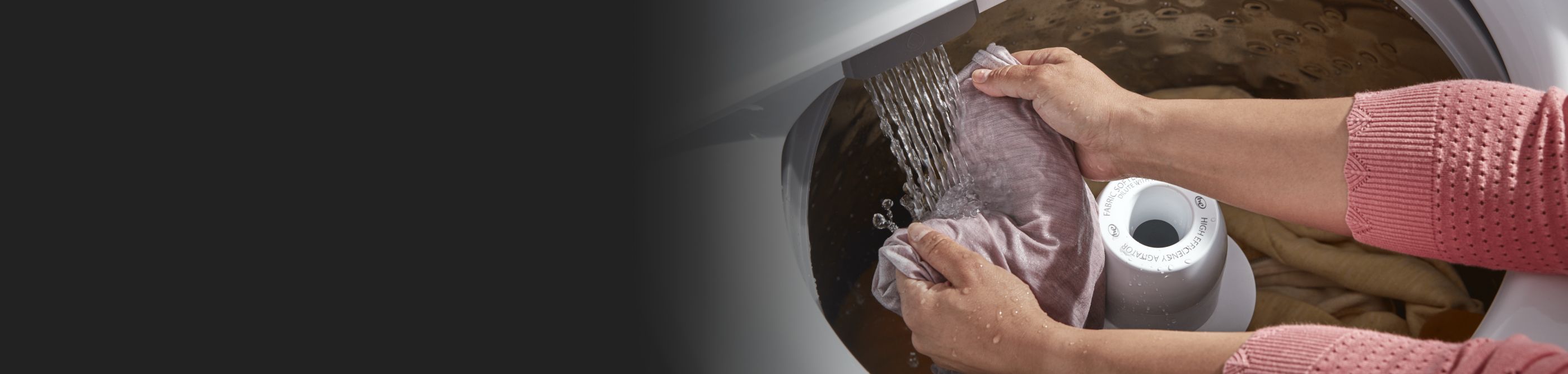 Person hand-rinsing laundry in a Whirlpool® Top-Load Washer