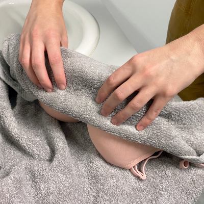 Person squeezing out excess water from a bra with a towel