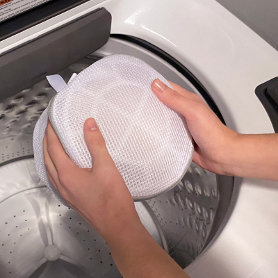 Mesh lingerie bag being placed inside a Whirlpool® washing machine