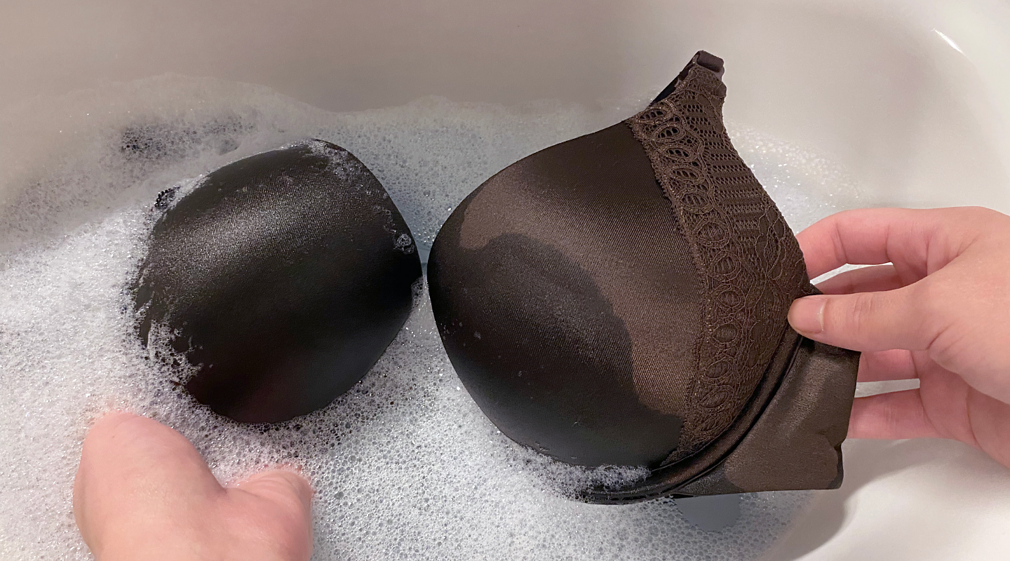 Person hand washing a brown bra