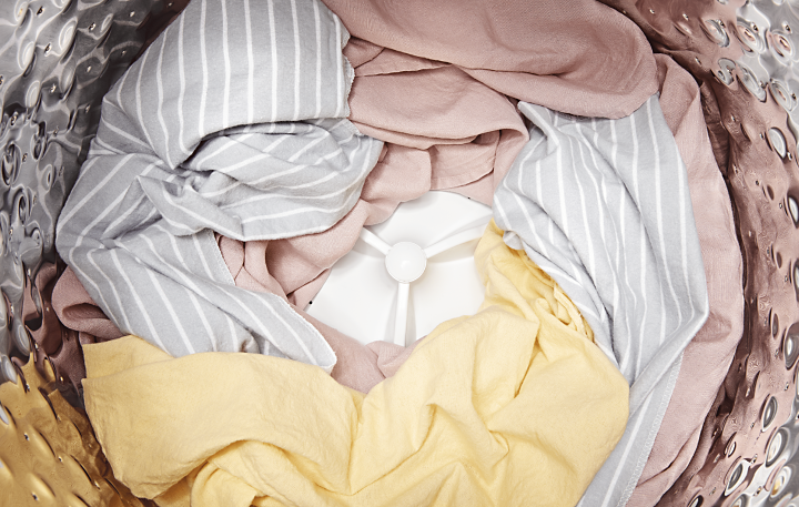Close-up of dry, pastel clothing in top-load washer.