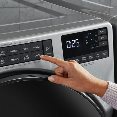 A finger pressing a laundry wash cycle