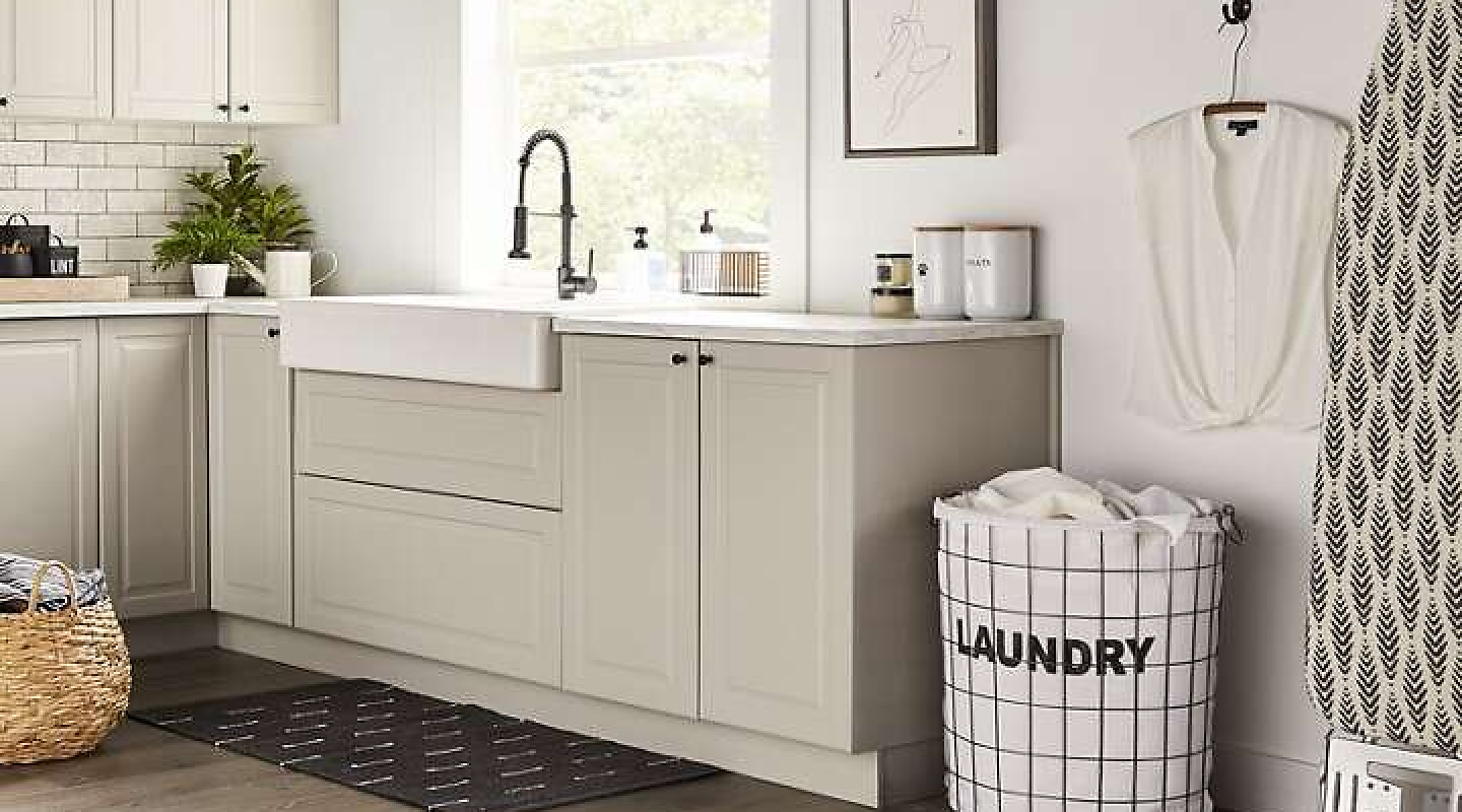 A laundry sink with beige cabinets in a modern laundry room.