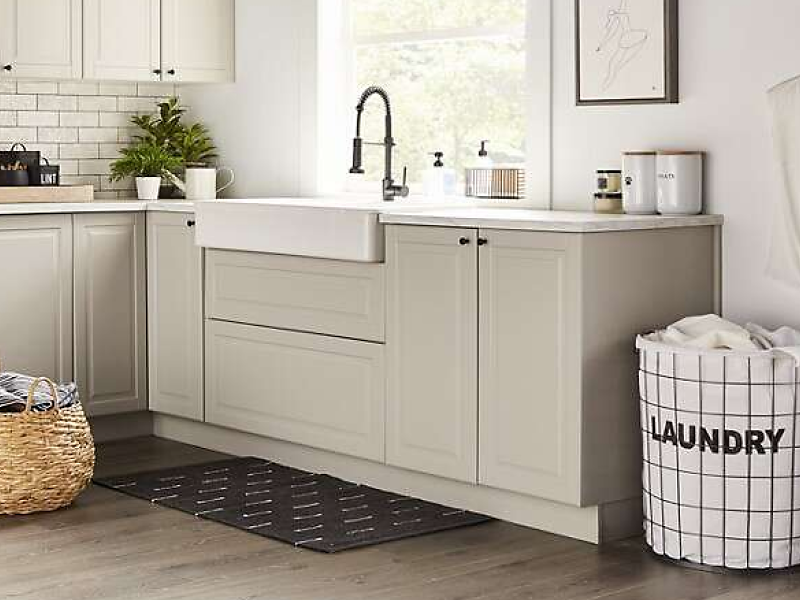 A laundry sink with beige cabinets in a modern laundry room.