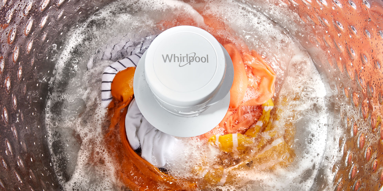 Orange clothes swirling in Whirlpool® Top Load Washer with an agitator