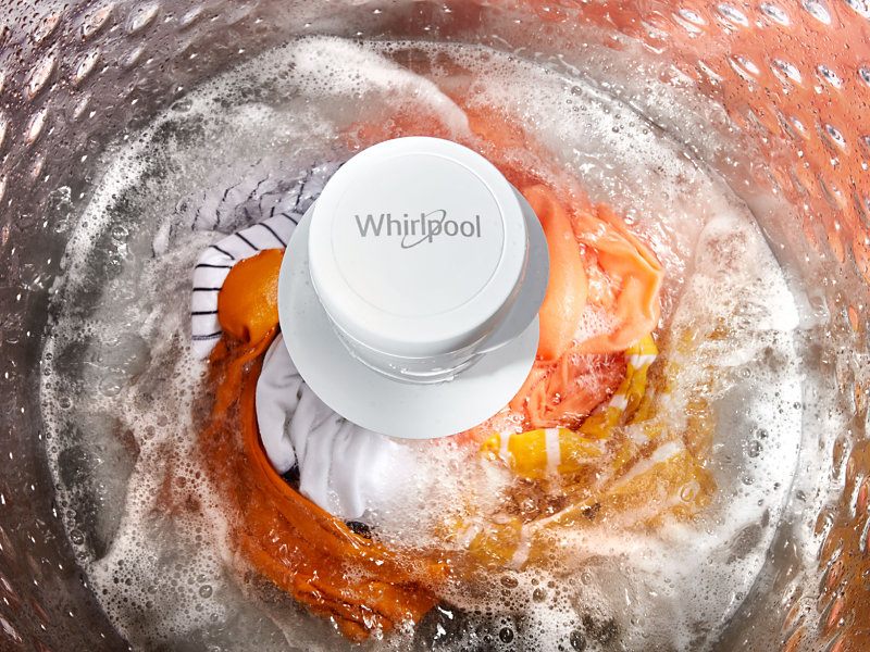 Orange clothes swirling in Whirlpool® Top Load Washer with an agitator