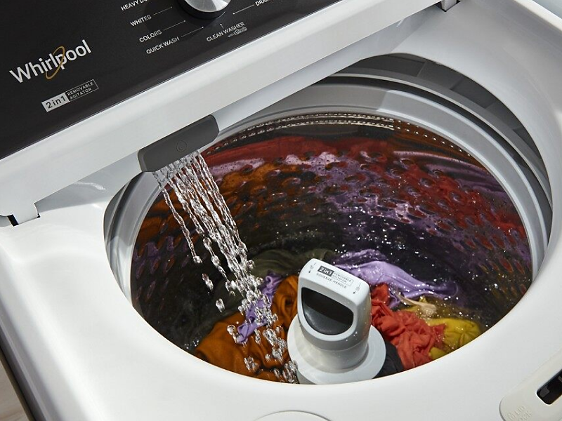 A closeup of a Whirlpool® top load washing machine filling with water.