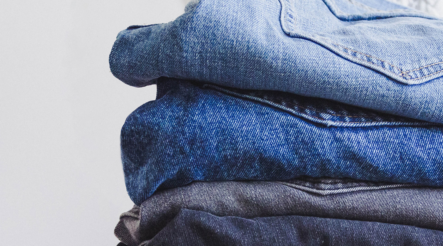 Four pairs of folded blue jeans.