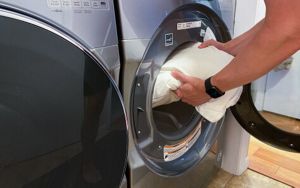 Man putting pillow into a washing machine