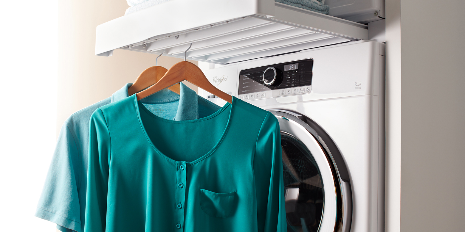 Two shirts hanging on a rack in front of a dryer