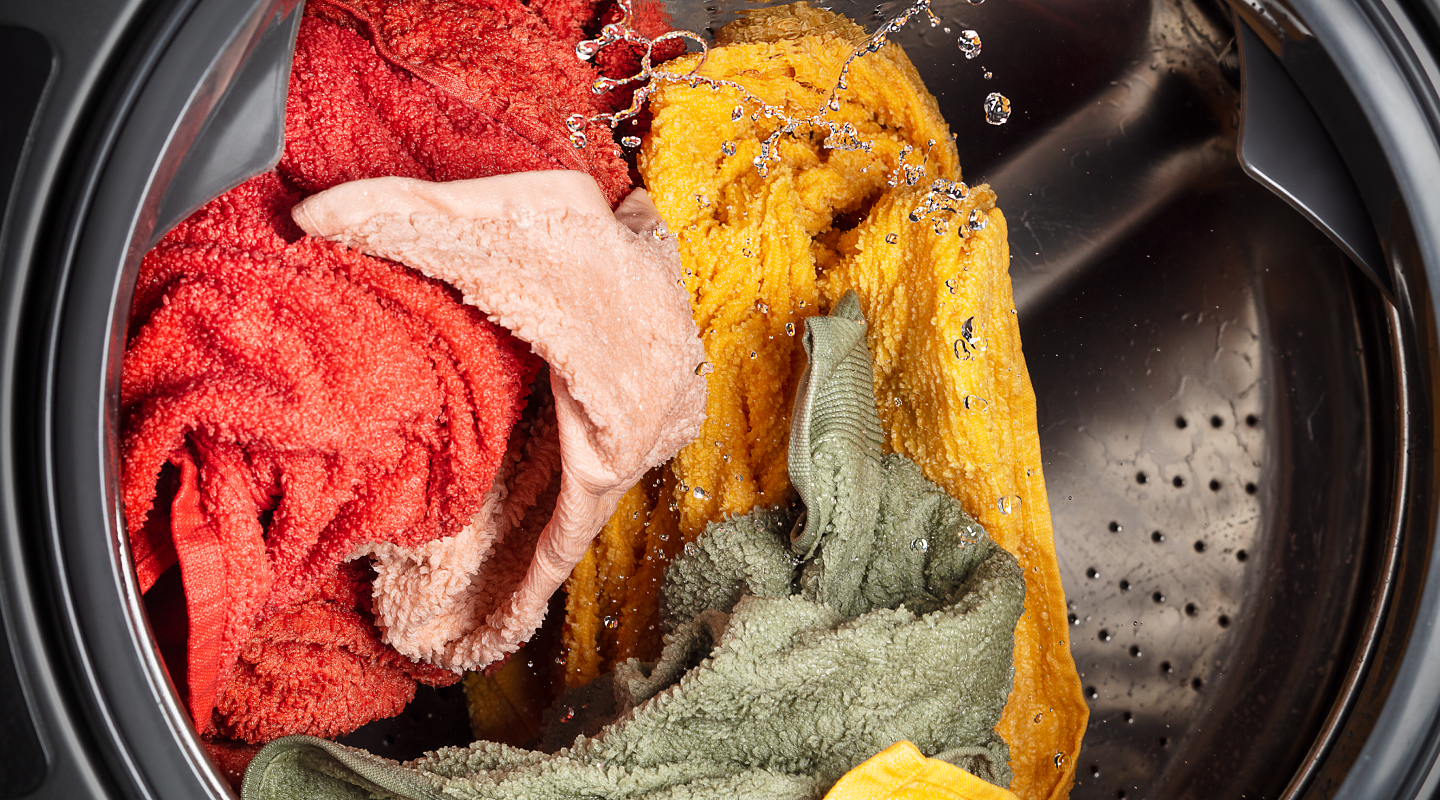 Towels of assorted colors being cleaned in a washing machine 