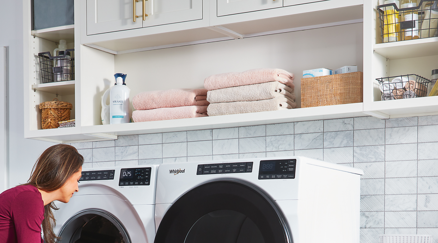 A woman washing towels with a Whirlpool® washer and dryer set