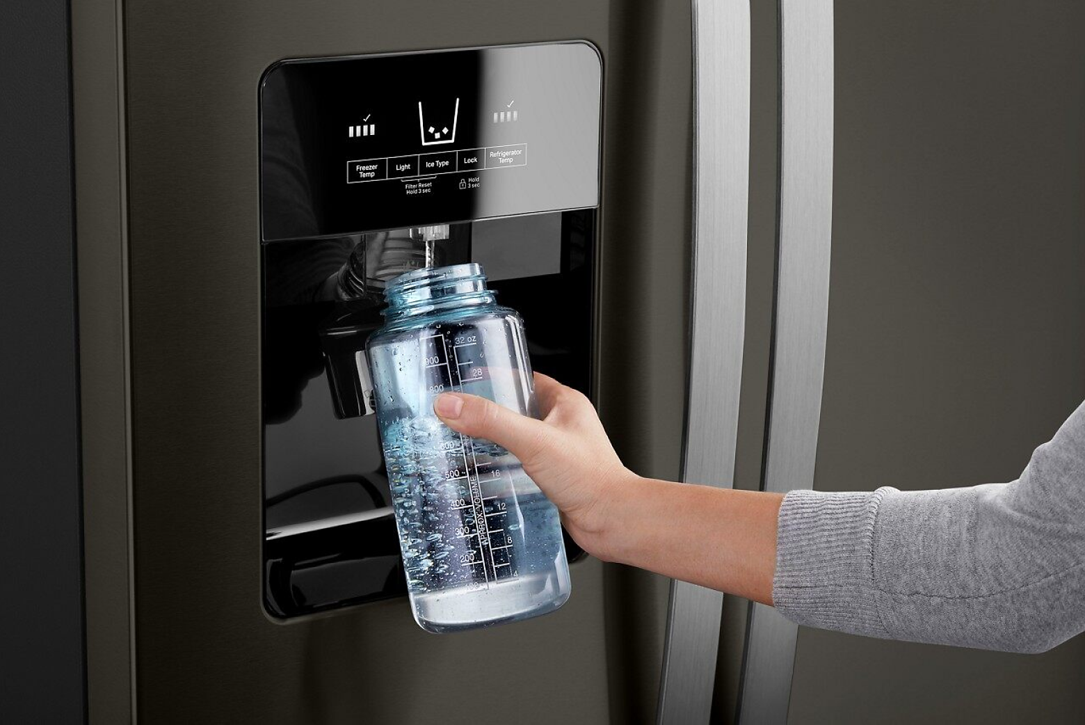 Hand filling water bottle beneath external refrigerator water dispenser